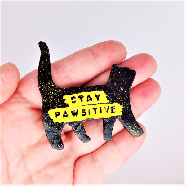 Magnet en forme de chat noir avec écrit à l'intérieur en jaune Stay pawsitive